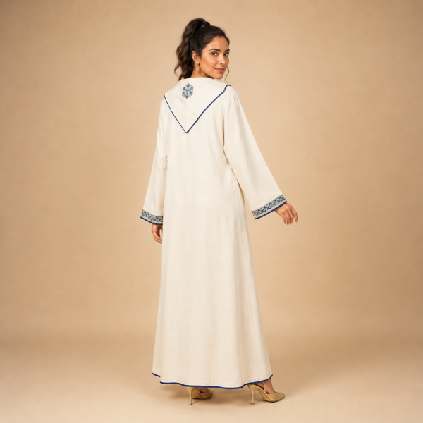 99 Back view of an ivory Moroccan djellaba with blue edging, patterned cuffs and a pointed hood with a small geometric accent